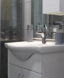 Apartman Amor Trebinje في تريبينيي: بالوعة بيضاء في الحمام مع مرآة