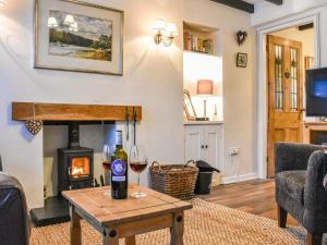 a living room with a fireplace and a glass of wine at Pan Cottage in Middleton