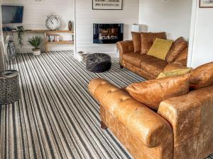 sala de estar con sofás de cuero marrón y chimenea en The Steps, en Pentewan