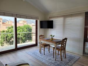ein Esszimmer mit einem Tisch und Stühlen sowie einem großen Fenster in der Unterkunft Leehaven Apartment in Hout Bay