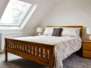 a bedroom with a wooden bed with a window at Druids Knowe in Tarfside