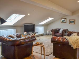 a living room with two leather couches and a tv at The Barn Pencoed Farm in Aberdare