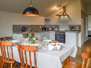 a kitchen with a dining table with a white table cloth at The Barn Pencoed Farm in Aberdare