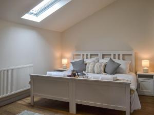 a bedroom with a large white bed with a skylight at The Barn Pencoed Farm in Aberdare