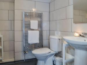 a white bathroom with a toilet and a sink at The Barn Pencoed Farm in Aberdare