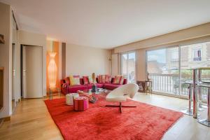 Les Cigognes - Deux Pièces - Deauville Centre في دوفيل: غرفة معيشة مع أريكة وسجادة حمراء