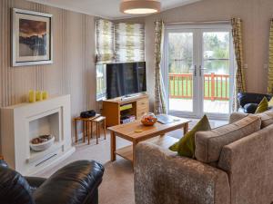 a living room with a couch and a tv at Lakeside in Kelsale