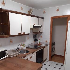 eine Küche mit weißen Schränken und einer Spüle in der Unterkunft Apartamento Brañavalera in Pola de Lena