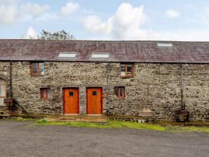 an old stone building with red doors and windows at Robins Nest - Uk36208 in Llanfihangel-y-creuddyn