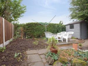 a patio with two white benches in a garden at The Coach House in Oswestry