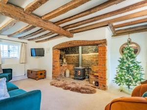 a living room with a fireplace and a christmas tree at The Cottage in Warborough