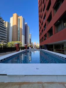 a swimming pool in a city with tall buildings at Top Flat Fortaleza in Fortaleza