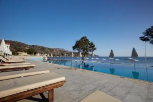 uma piscina com espreguiçadeiras e o oceano em Giannoulis - Grand Bay Beach Resort (Exclusive Adults Only) em Kolymvari