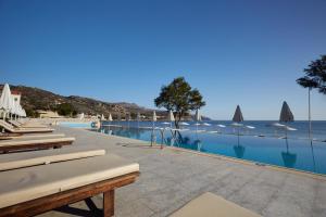 a swimming pool with lounge chairs and the ocean at Giannoulis - Grand Bay Beach Resort (Exclusive Adults Only) in Kolymvari