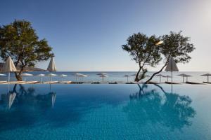 - une piscine avec des parasols et l'océan dans l'établissement Giannoulis - Grand Bay Beach Resort (Exclusive Adults Only), à Kolymbari