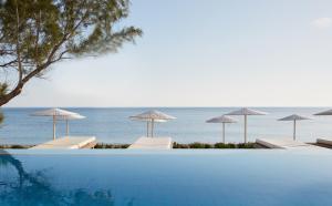 科林瓦里奧的住宿－Giannoulis - Grand Bay Beach Resort (Exclusive Adults Only)，海滩上带椅子和遮阳伞的游泳池