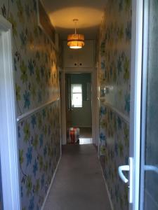 un pasillo con papel pintado con motivos florales y una lámpara de araña en Apartment with shared garden and basic equipments en Plymouth