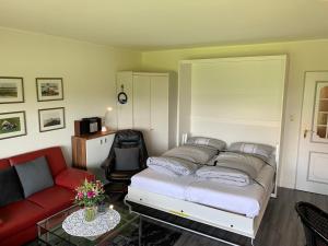 ein Schlafzimmer mit einem Bett und einem roten Sofa in der Unterkunft Ferienwohnung "Palstek" im Haus Düwelswarft in Sankt Peter-Ording