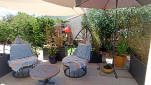 due sedie e un tavolo e un ombrellone su un patio di Escale à Bouzigues a Bouzigues