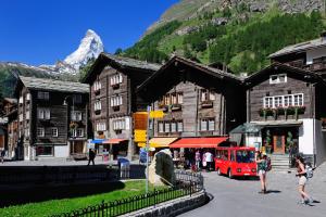 a town with a red train in front of a mountain at Hotel Simi in Zermatt