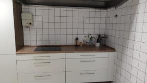 una cocina con armarios blancos y paredes de azulejos blancos. en Zimmer in Ramstein, en Ramstein-Miesenbach
