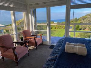 a bedroom with a bed and chairs and a view of the ocean at Seacroft Beach House in Sugarloaf