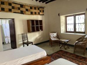 a bedroom with two beds and two chairs and two windows at Casa Fabula in Ilha de Moçambique