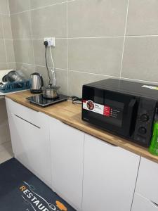 a black microwave sitting on a counter in a kitchen at 家好月圆 Sweet Home in Kampong Seri Gading