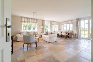 a living room with white furniture and a table at Haus Deichblick 1 in Dunsum