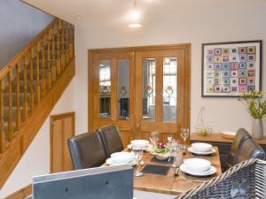 a dining room with a wooden table and chairs at Waterside Cottage in Winewall