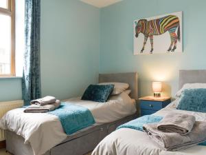 a bedroom with two beds and a zebra picture on the wall at Waterside Cottage in Winewall