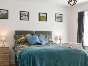 a bedroom with a bed with blue sheets and pillows at Derwent Apartment in Glossop