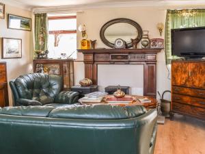 uma sala de estar com um sofá de couro e uma televisão em Byeways - Railway Carriage em Selsey