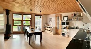 a kitchen with a wooden ceiling and a wooden table at Spacey and charming cabin 300 m. from beach in Tjørneholm