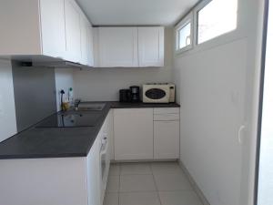 a small kitchen with white cabinets and a microwave at La Bernaudine bis in Annonay