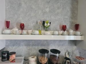 un estante con tazas, tazones y copas de vino en Petalo rosso, en Pegognaga