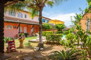 a courtyard with a palm tree and a yellow umbrella at Flats vila bela Búzios in Búzios