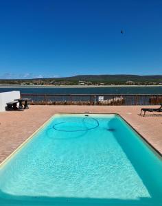 a large blue swimming pool with a view of the ocean at River View Cottage - at the Breede in Witsand