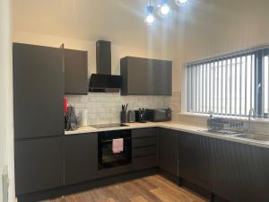 a kitchen with grey cabinets and a sink at Sapphire Premier Apartments w/Secure Parking in Cardiff