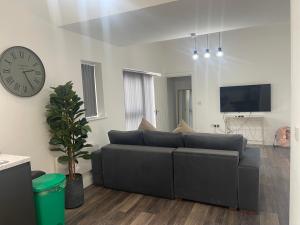 a living room with a couch and a clock on the wall at Sapphire Premier Apartments w/Secure Parking in Cardiff