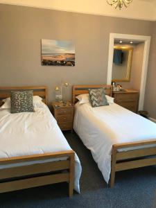 1 dormitorio con 2 camas y espejo en West End Guest House, en Elgin