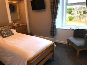 a bedroom with a bed and a window and a chair at West End Guest House in Elgin