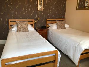 two beds sitting next to each other in a room at West End Guest House in Elgin