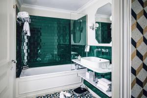 فندق غراند بيغال  في باريس: حمام مع حوض ومغسلة ومرآة