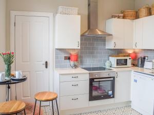a kitchen with white cabinets and a stove top oven at The Seaside Suite in Helensburgh