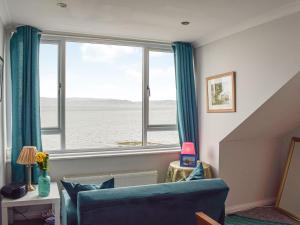 a living room with a blue couch and a large window at The Seaside Suite in Helensburgh