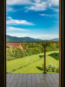 ein Fenster mit Blick auf einen Garten mit Bergen im Hintergrund in der Unterkunft Białe Chyże in Wetlina