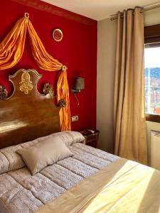 a bedroom with a bed with a red wall at Almunia de San Miguel in Toledo