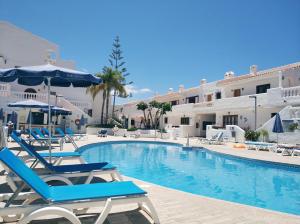 una piscina con sillas y sombrillas junto a un hotel en SEAVIEW PORT ROYAL, Los Cristianos, Heated Pool, WiFi, en Los Cristianos