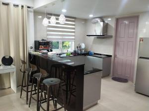 una cocina con encimera negra y taburetes de bar en Santubong Suites Sejinjang en Kuching